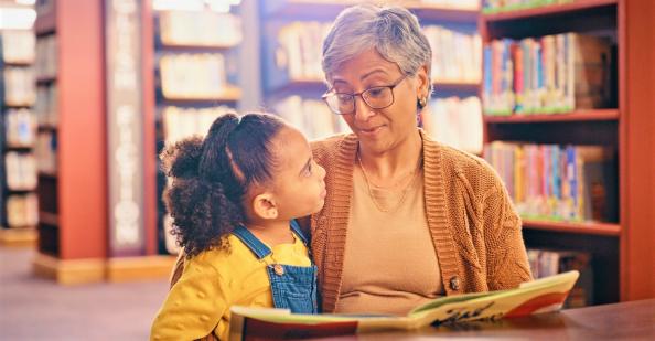 Girl and grandmother reading in library