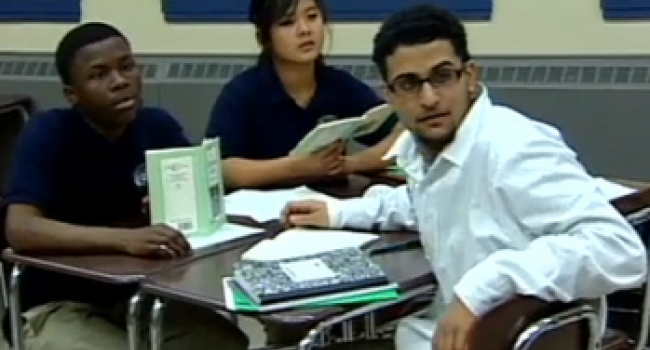 Four students sitting at desks and looking at someone off-camera