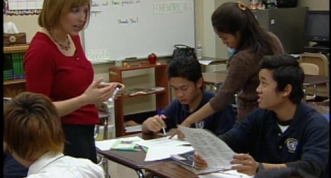 two adults helping two students with their work