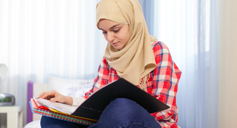 Teenage Muslim girl studying in room