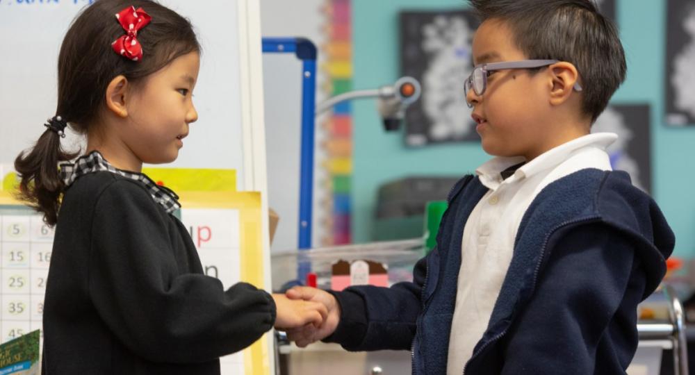 Girl and boy shaking hands in classroom